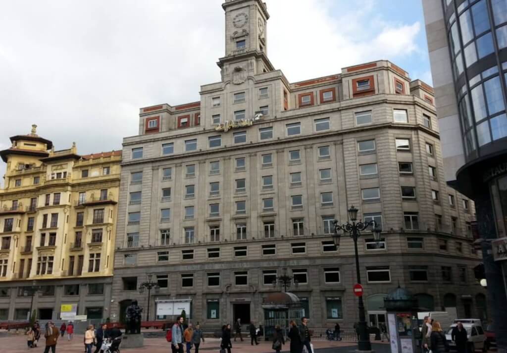 Vista de la fachada de la sede de Cajastur, situado en una plaza en un entorno peatonalizado y con un gran reloj coronando el edifico
